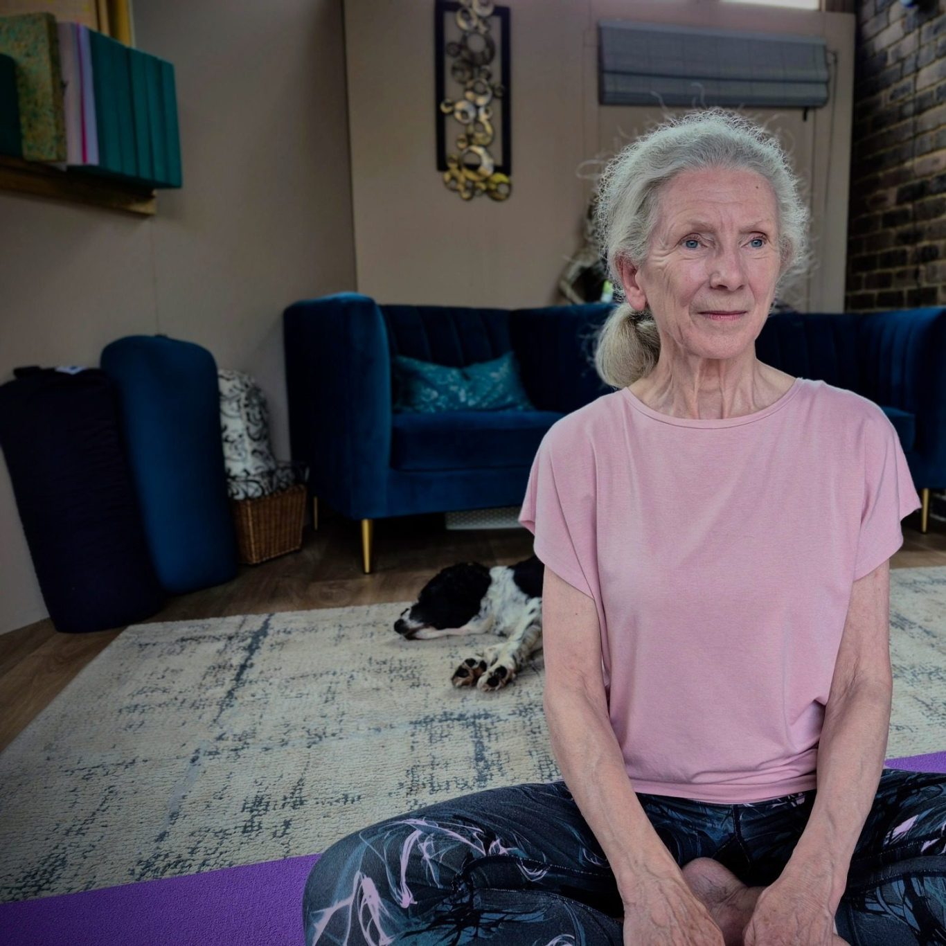 yoga lady claire yoga Elderly woman seated in a yoga pose, smiling, with a dog resting nearby.